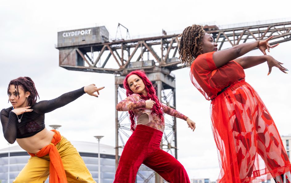 Three woman in colourful clothing dancing.