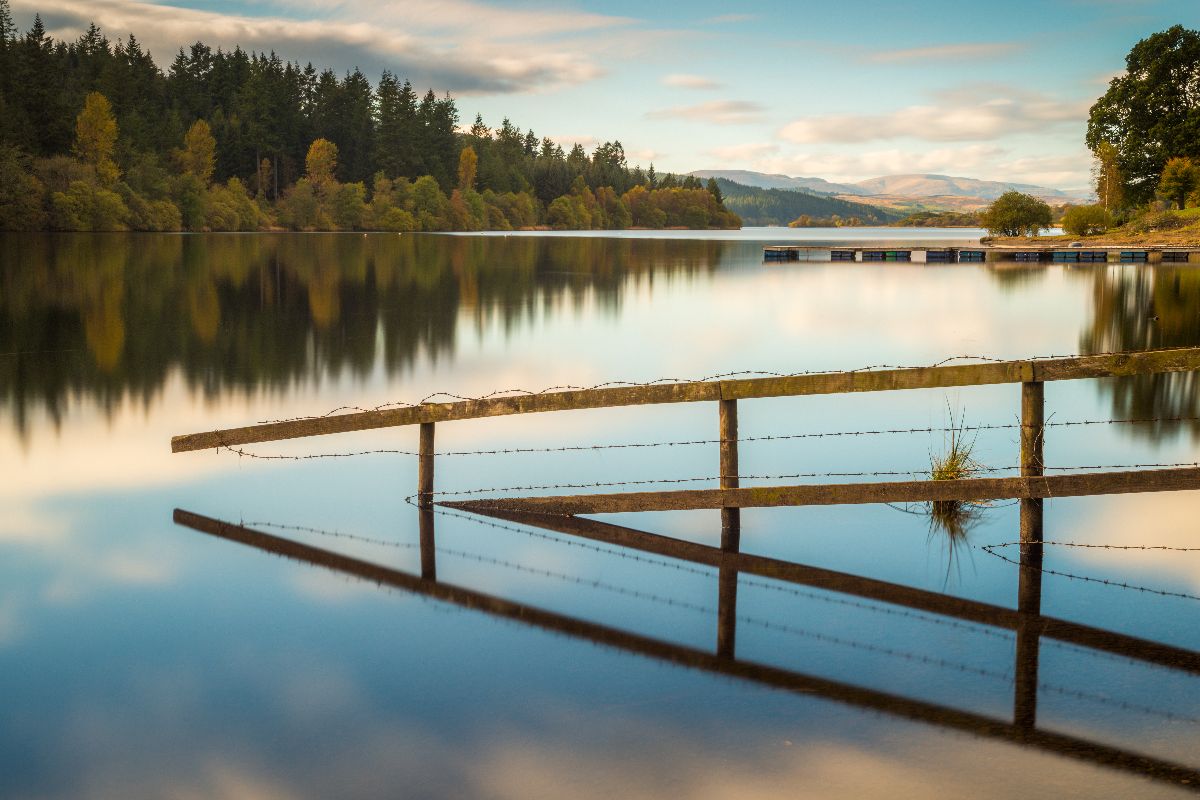 Scenic view of mountains and loch with water still.