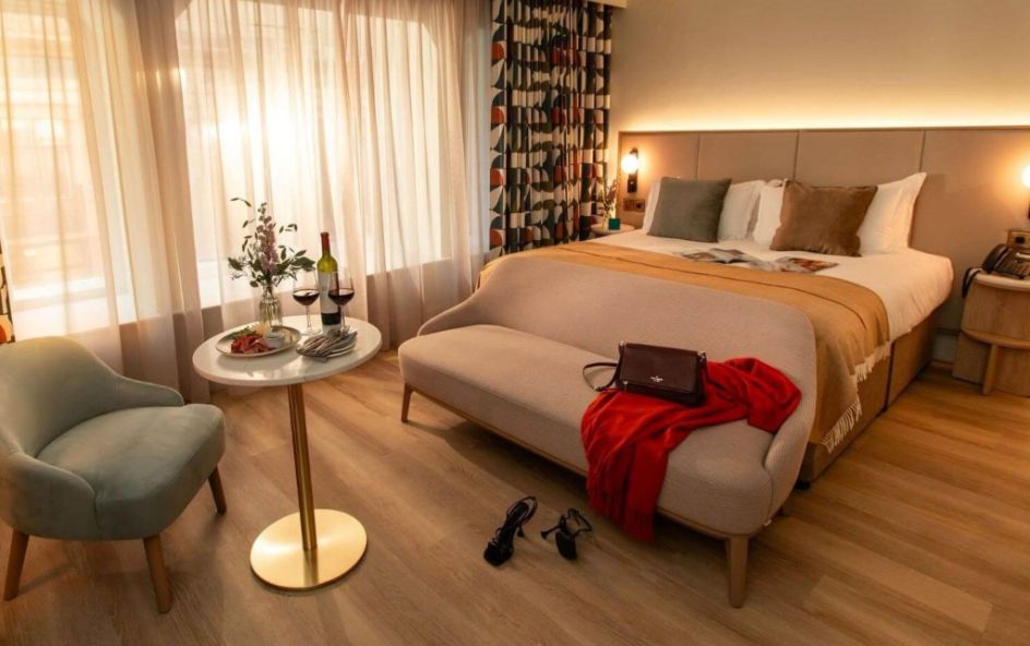 A cozy hotel room featuring a neatly made bed with beige and brown pillows.