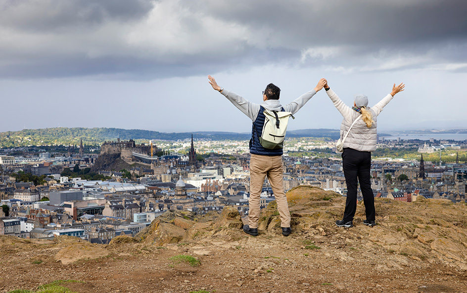 Couple with arms raised looking over city.