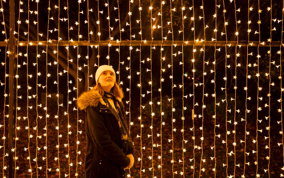 A person standing in front of a wall of string lights