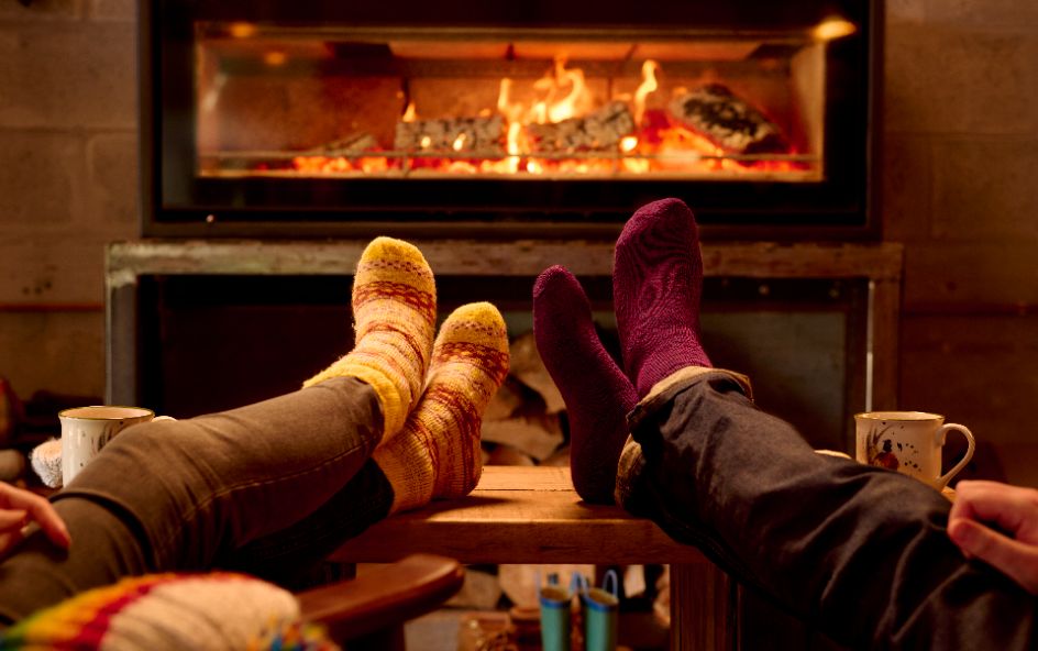 Two people with their feet in socks beside cosy fire