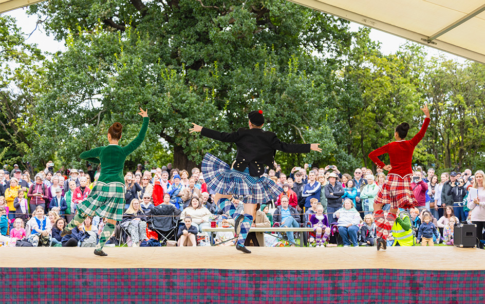 Ceilidh dancers on stage performing to crowd.