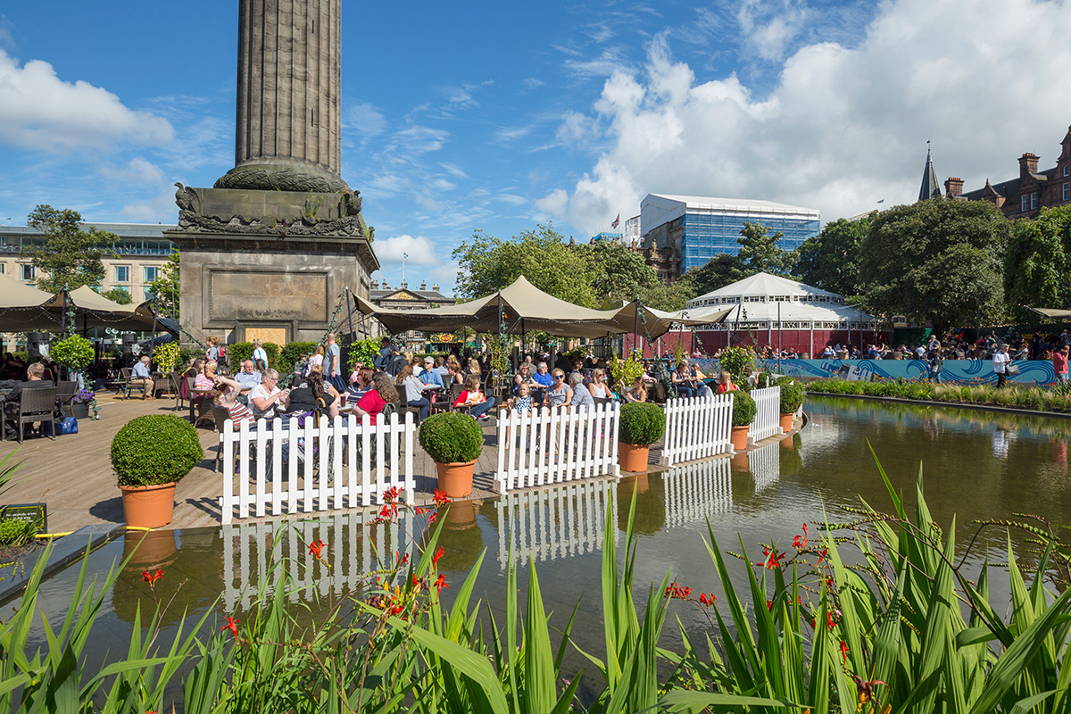 People sat around statue enjoying the sunshine