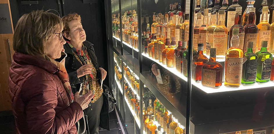 Two people standing in front of shelves of whisky