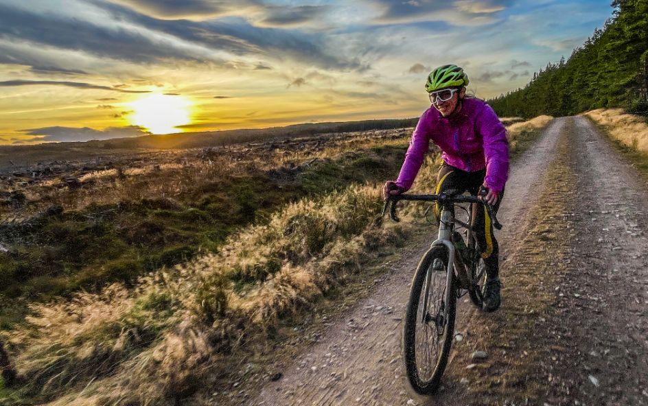 Person riding bike on track with sun setting.