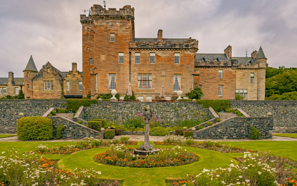 A large red sandstone castle with fountain in front of it