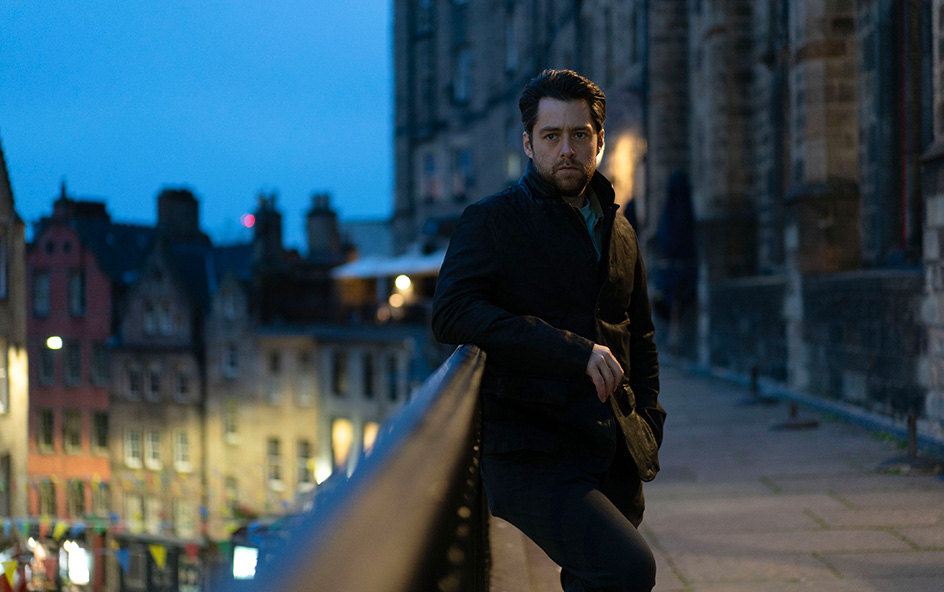 Man leaning against railings against city backdrop