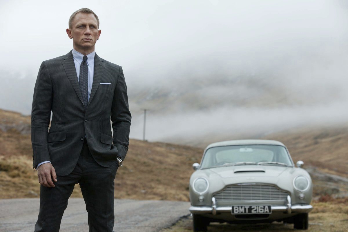 Man standing next to a car, with misty mountains in the background.