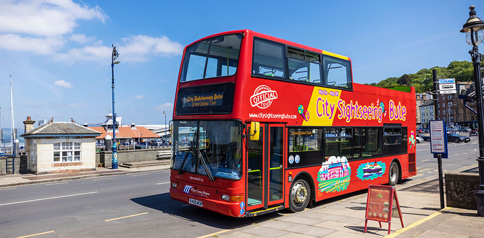 a red and yellow double decker tour bus at a bus stop