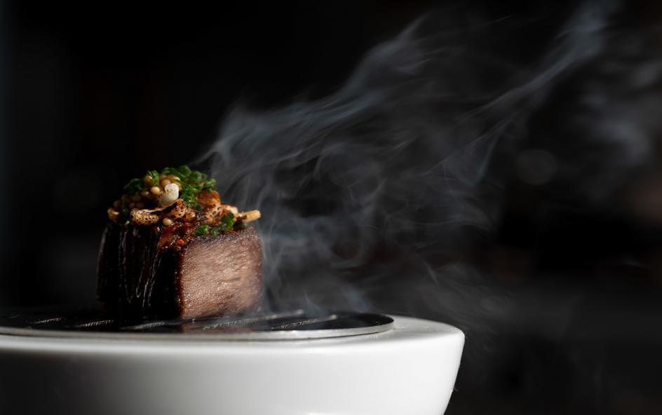 A cooked piece of meat on a plate, with steam rising from it.
