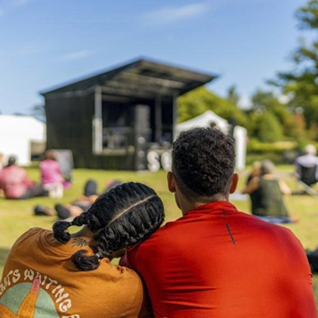 People sitting in a field in front of a stage