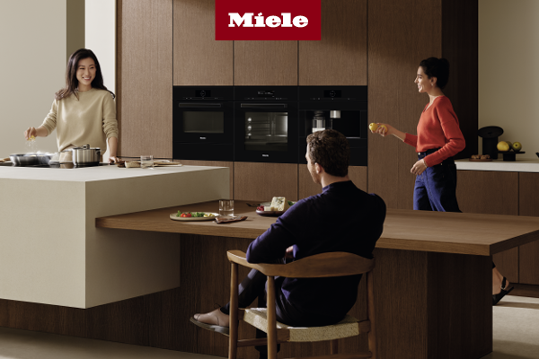 Man serving food that came from a Miele oven to friends sitting at dinner table 