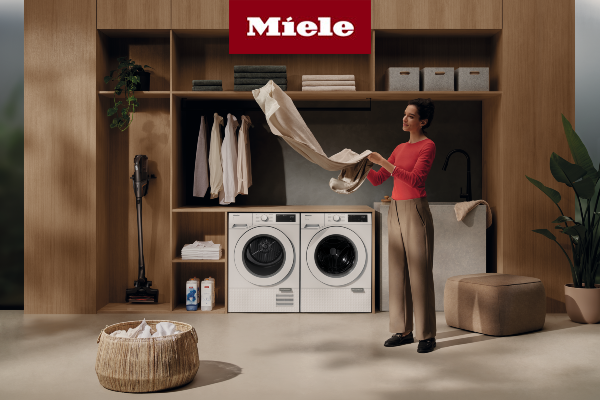 Woman folding piece of clothing in front of Miele laundry machines 