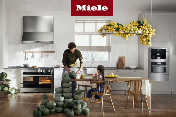 A man and a child standing in a kitchen featuring fall decor and miele appliances 