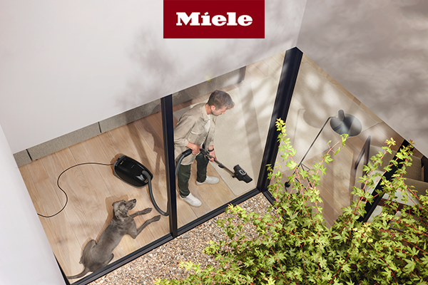 Man vacuuming floor with Guard M1 Cat & Dog next to dog 