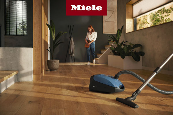 Woman walking down steps towards Miele Classic C1 vacuum cleaner 