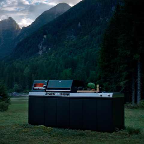 Eine Miele Outdoor-Küche auf einer Waldlichtung in der Abenddämmerung.