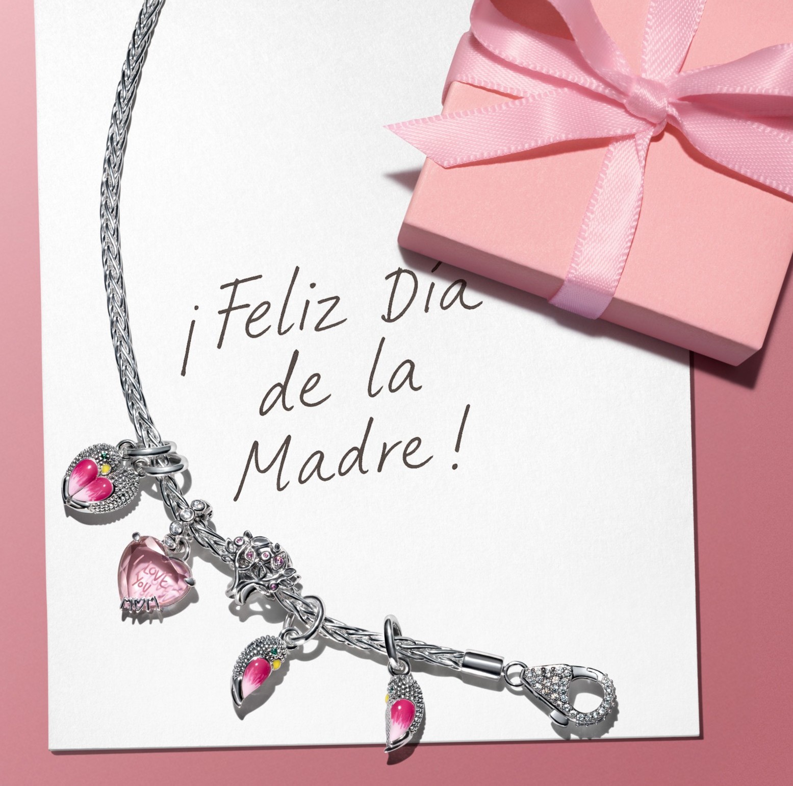 Charms styled on a bracelet over a note that says Happy Mother's Day. 