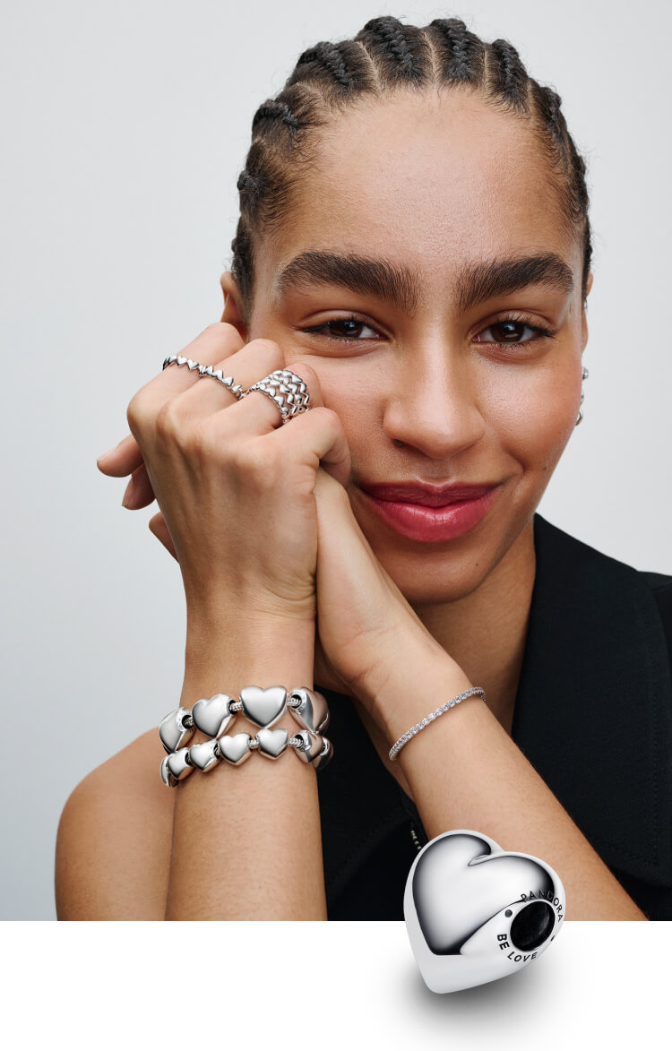 Model wears bracelet loaded with the Be Love Heart Charm and Pandora jewelry