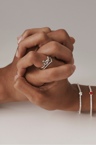 Hands holding each other wearing Pandora jewellery