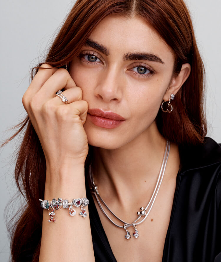 Model wears Disney x Pandora necklace, charm bracelet and earrings