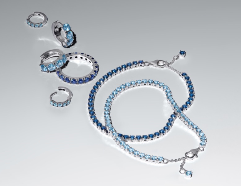A selection of blue and sterling silver Pandora Timeless jewellery on a grey background.
