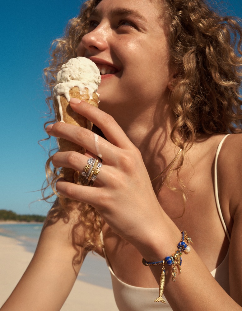 A model holds an ice cream and wears a Pandora Moments bracelet with charms.