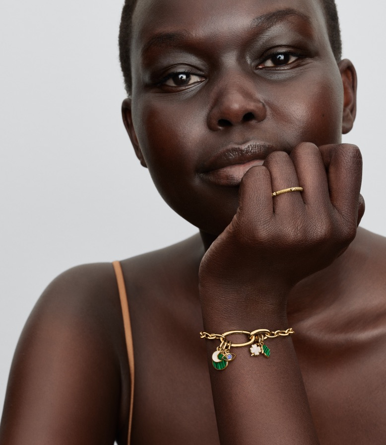 Model care poartă o brățară Pandora ME cu zale, placată cu aur de 14k, prevăzută cu talismane.