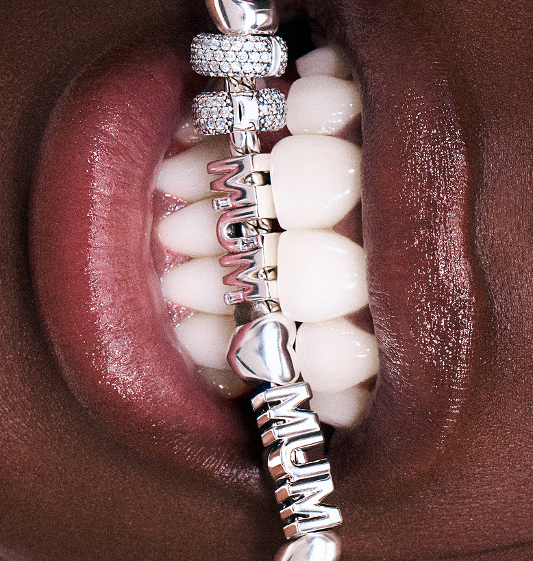  A modell Mum feliratú charm karkötőt tart a fogai között