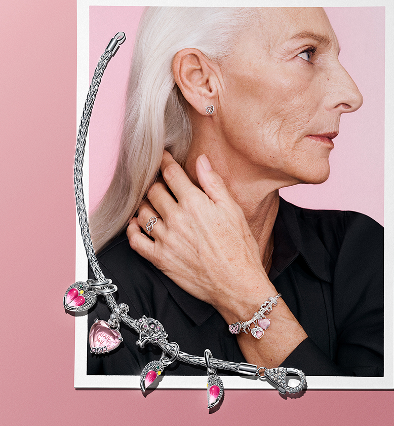 A sterling silver charm bracelet on top of a photo of an older model styled with a sterling silver charm bracelet. 