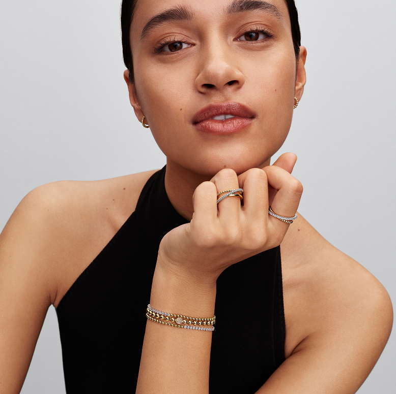 A model styles bracelets, rings and earrings with contrasting metals and textures