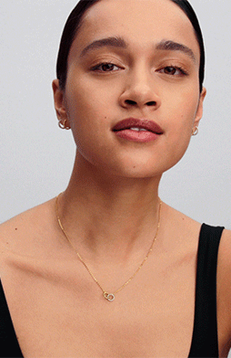A model styles a mixed-metal necklace with earrings